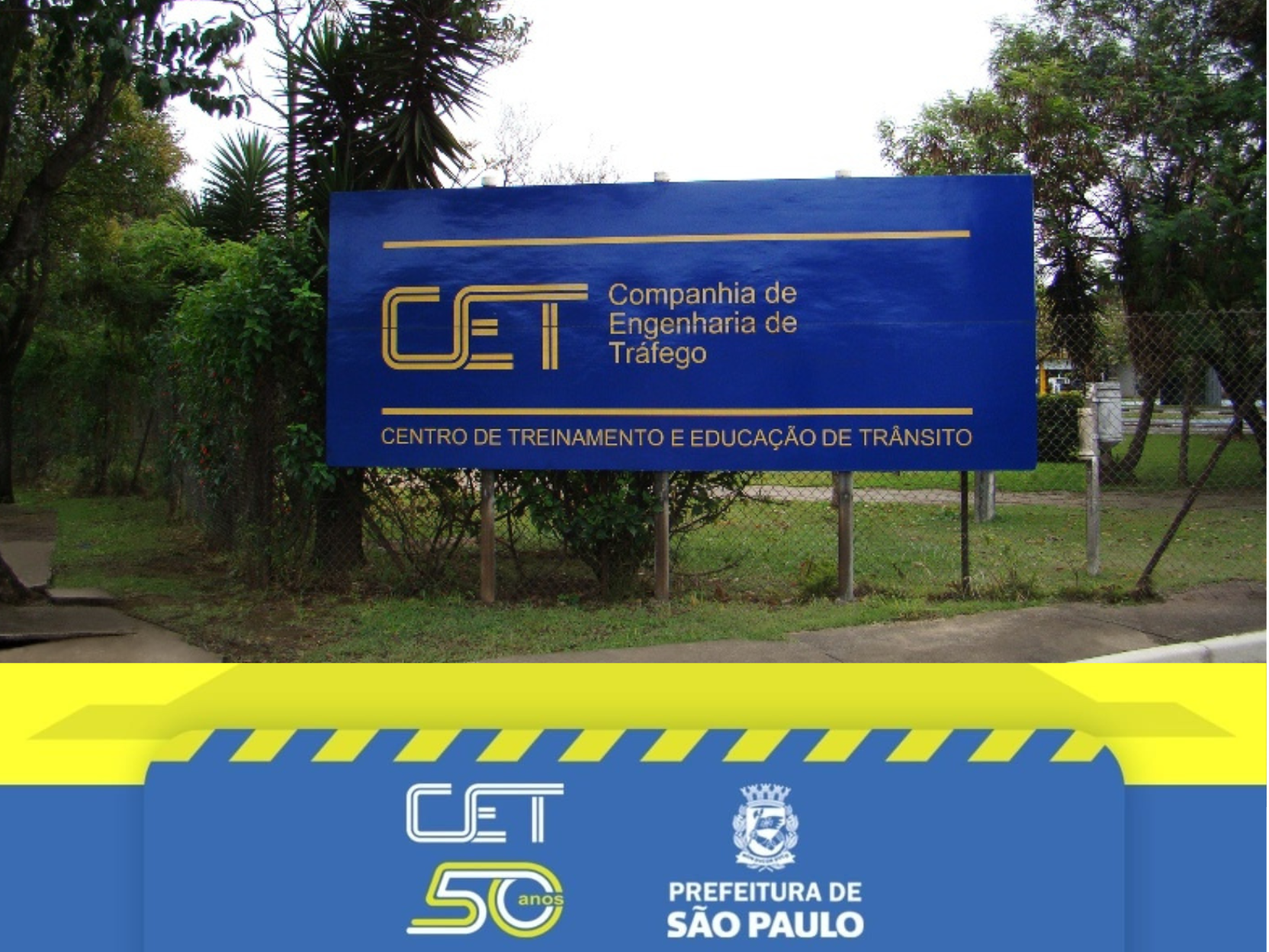 A imagem mostra a entrada do Centro de Treinamento e Educação de Trânsito (CETET), pertencente à Companhia de Engenharia de Tráfego (CET) de São Paulo.
No centro da imagem há uma placa grande retangular azul, fixada em dois postes metálicos e posicionada em frente a uma cerca de arame.
Sobre a placa, em letras amarelas, está escrito: “CET – Companhia de Engenharia de Tráfego”e logo abaixo: “Centro de Treinamento e Educação de Trânsito”.
O entorno da placa tem gramado verde, árvores e arbustos, sugerindo um ambiente arborizado e tranquilo.
Na parte inferior da imagem, há uma faixa gráfica institucional, em tons de azul e amarelo, com o logotipo comemorativo de 50 anos da CET, ao lado do brasão da Prefeitura de São Paulo e a inscrição: “Prefeitura de São Paulo”. (Descrição: Deisy Paula S. S. Gabriel)